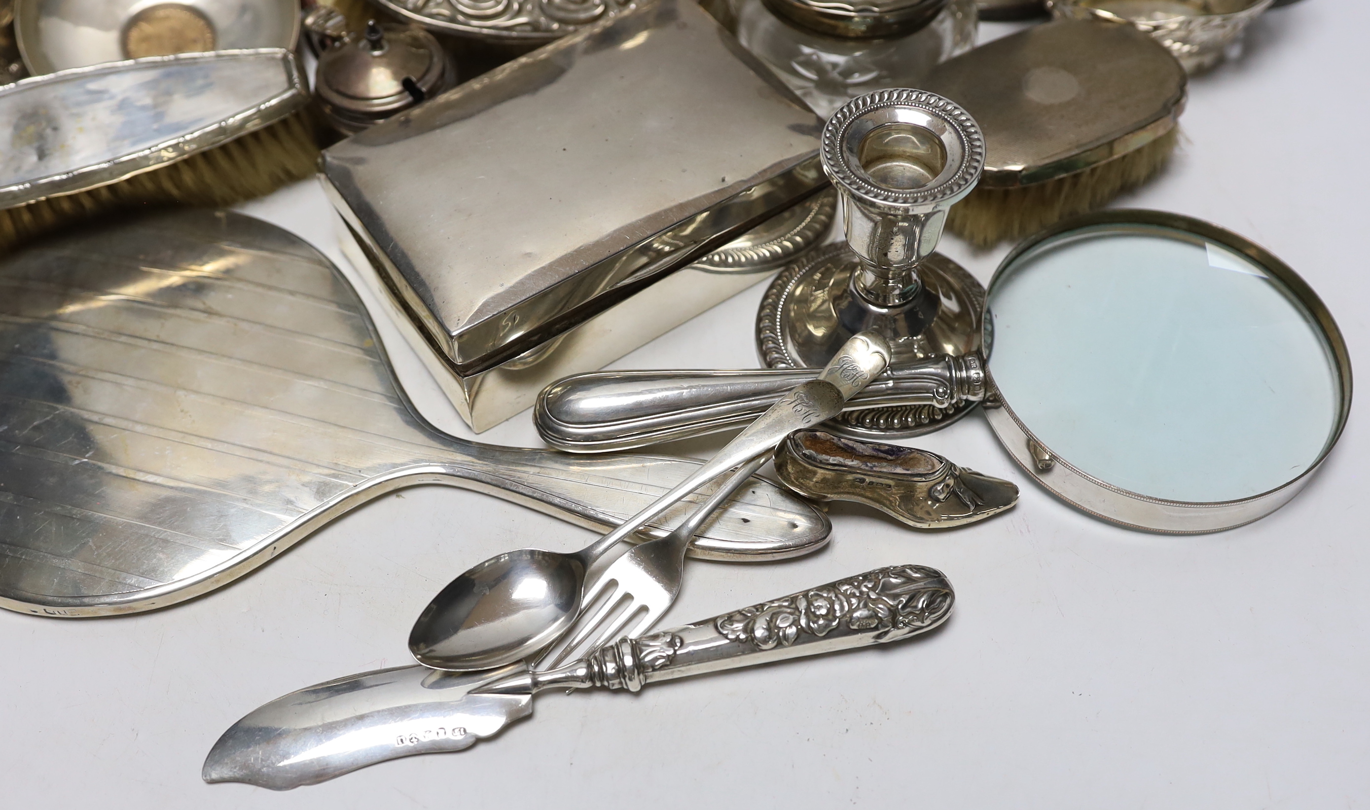 Sundry silver items including a pair of candlesticks, marks rubbed, handled magnifying glass, lidded vase, hand mirror, five brushes, cigarette box, trinket box, toilet jar and eleven other items including a novelty shoe
